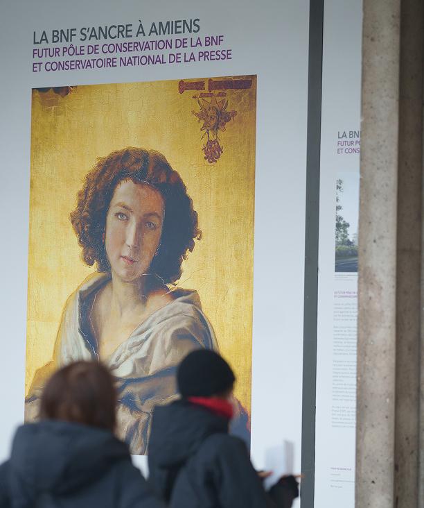 Deux personnes sont au premier plan, derrière eux, un visuel XXL faisant partie d'une exposition organisée en partenariat avec la Bibliothèque nationale de France.