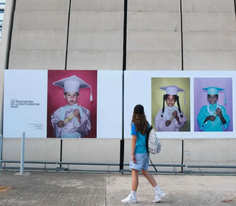 Un enfant se tient devant 3 photos XXL habillant la façade d’Avignon TGV. Ces images sont exposées dans le cadre d’un partenariat avec les Rencontres de la photographie d’Arles.
